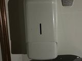 a white paper towel dispenser in the corner of a room