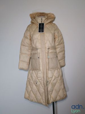 un manteau à capuche posé sur un mannequin contre un mur blanc