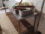 une cuisine avec une table en métal sur laquelle s'entassent toutes sortes d'objets