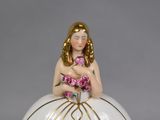 a figurine of a woman in a ball gown holding a bouquet of flowers