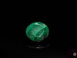 a close up of a green stone on a black surface