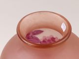 a pink vase with purple flowers in it sitting on a table
