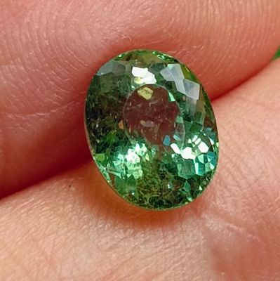 green tourmaline gems are being held in a person ' s hand
