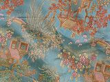 a close up of a blue fabric with a pattern of birds and flowers on it