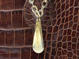 brown alligator skin handbag with a gold chain and a tag on the handle