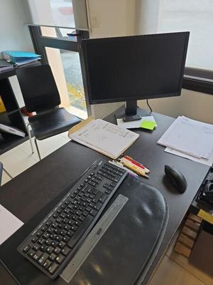 un bureau sur lequel se trouvent un clavier, un écran, une souris et d'autres objets