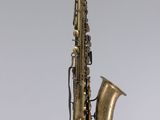 un gros plan d'un saxophone posé sur un pupitre, sur fond blanc
