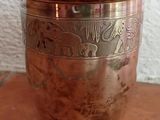 a metal cup that is sitting on a wooden table
