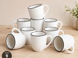 six tasses à café blanches à bord noir posées sur une table en bois