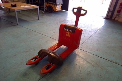 a red fork lifter sitting on the floor in a garage