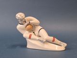 une figurine représentant un homme assis sur une planche de surf