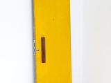 une porte jaune avec une poignée marron dans une pièce blanche