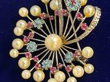 an image of a brooch with pearls and crystals on a blue surface