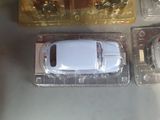 a white toy car in a plastic container next to other toy cars