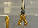 a pair of scissors sitting next to a gold object