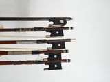Quatre types différents d'archets de violon sont alignés sur un fond blanc
