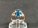 a ring with a blue topaz stone on a clear stand