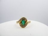 an emerald and diamond ring on a white surface