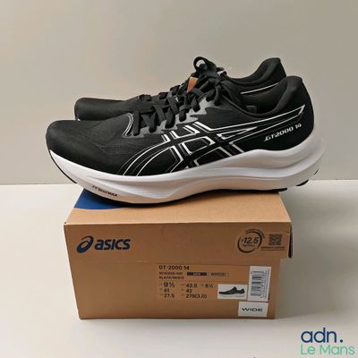 des chaussures de course Asics posées sur une boîte, sur une surface blanche