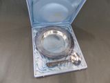 un plateau en argent avec une cuillère et un repose-cuillère, dans une boîte bleue