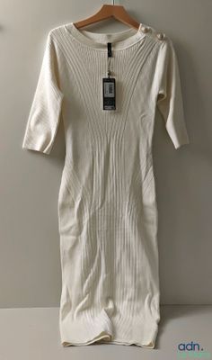une robe blanche suspendue à un cintre accroché au mur