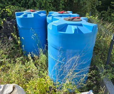 two blue barrels sitting next to each other in the grass