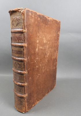 an old brown book sitting on top of a table next to a gray wall
