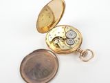 a small gold pocket watch sitting on a white surface