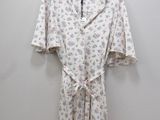 a white shirt with a floral print on it hangs on a hanger