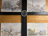 quatre tableaux accrochés au mur d'un immeuble sur lequel se trouve une horloge