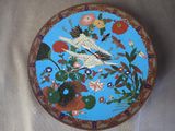 une assiette bleue ornée d'un oiseau et de fleurs