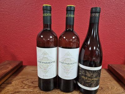 three bottles of wine sit on a table in front of a red wall