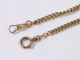 a close up of two gold chains on a white surface