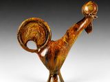 un gros plan d'une figurine représentant un coq posée sur une surface blanche