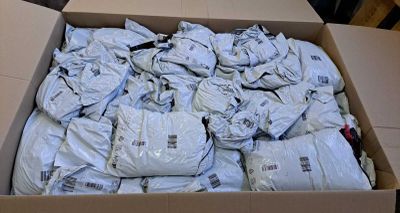 a cardboard box filled with bags of clothes on the floor