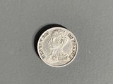a close up of a silver coin on a gray surface