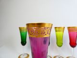 brightly colored wine glasses are lined up on a white surface