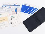 a black wallet and some boarding cards on a white table