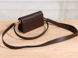 brown leather cross body bag with gold hardware on wooden table