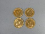 quatre types différents de pièces d'or sur une surface blanche
