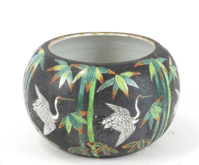 un vase noir orné d'un motif représentant des grues et des bambous