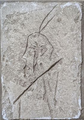 une image représentant la sculpture d'un homme tenant une lance, gravée dans la pierre