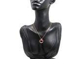 black mannequin head with a pink necklace on a white background