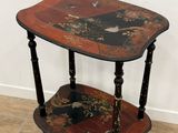 a small wooden table with a black and red design on it