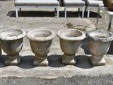 four stone vases sitting on a concrete slab