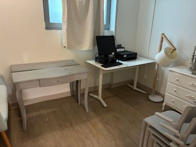 un bureau blanc sur lequel se trouve un ordinateur, dans un coin de la pièce