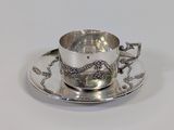 a silver tea cup and saucer on a saucer