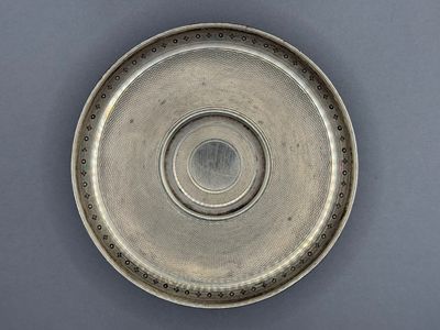 un gros plan d'une assiette en argent posée sur une surface grise