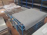 un chariot métallique sur lequel est posé un matelas, dans un entrepôt