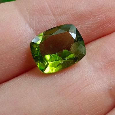 un gros plan sur la main d'une personne tenant une pierre précieuse verte